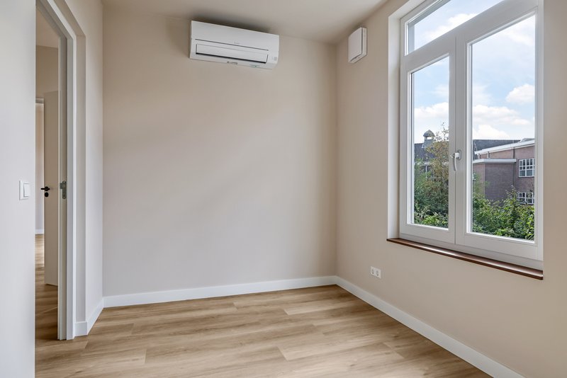 Slaapkamer van appartement 188B met groot raam en airconditioning