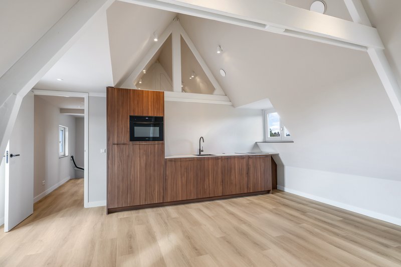 Open keuken van appartement 188C met houten fronten en zichtbare witte dakbalken