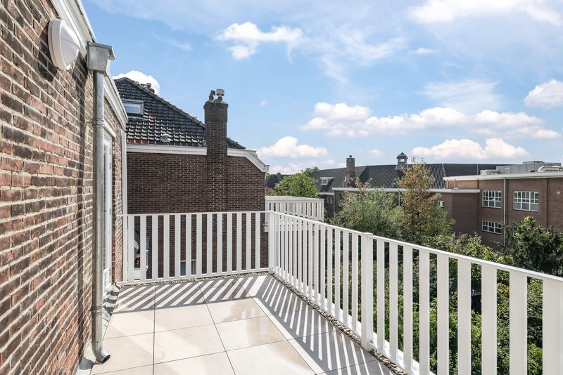 Dakterras van appartement 188C met witte balustrade en uitzicht op de omgeving