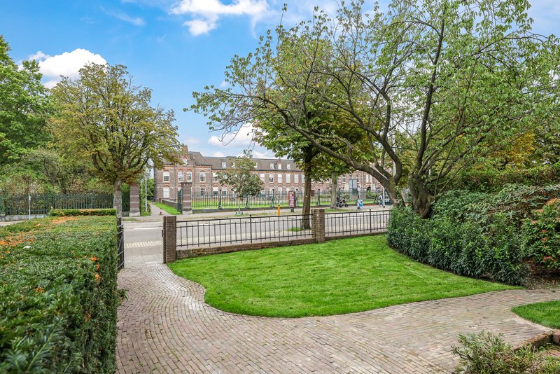 Voortuin bij appartement 188 met gazon, bomen en uitzicht op de Groesbeekseweg