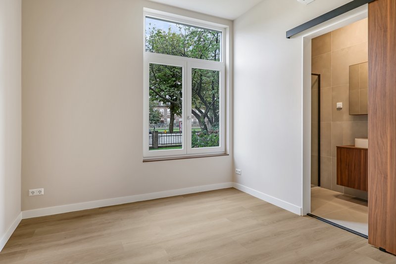 Slaapkamer met raam en toegang tot de badkamer van appartement 188
